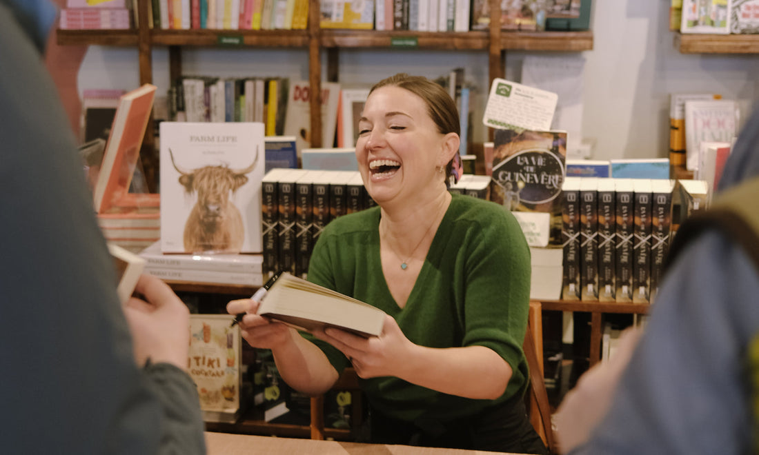 Author Paula Lafferty laughs and signs books at an event at Monstera's Books in Kansas City